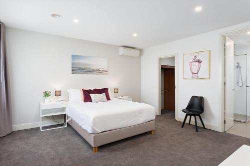 a white bedroom with a bed and a chair at Boutique Stays - Mentone Abode in Mentone