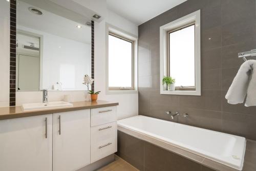 a bathroom with a tub and a sink and two windows at Boutique Stays - Mentone Abode in Mentone
