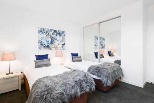 a bedroom with two beds and a mirror at Boutique Stays - Murrumbeena Place 1 in Carnegie