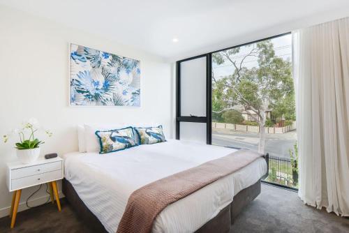 a bedroom with a large bed and a large window at Boutique Stays - Victoria Road in Melbourne