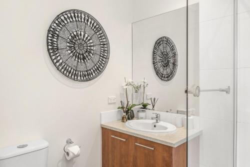 a bathroom with a sink and a toilet and mirrors at Boutique Stays - The Richardson in Mentone