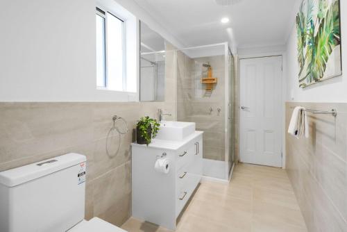 a white bathroom with a sink and a shower at Boutique Stays - Carlton Terrace in Melbourne