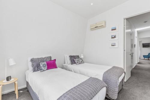 two beds in a room with white walls at Boutique Stays - Port Haven in Melbourne
