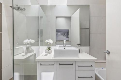 a white bathroom with a sink and a mirror at Boutique Stays - Port Haven in Melbourne