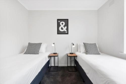 two beds in a room with two side tables at Boutique Stays - Ace's Place in Melbourne