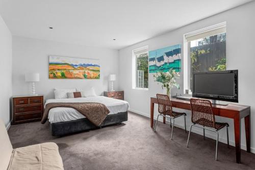 Schlafzimmer mit einem Bett und einem Schreibtisch mit einem TV in der Unterkunft Boutique Stays - Lalique in Melbourne