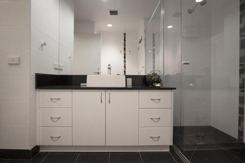 a white bathroom with a sink and a shower at Boutique Stays - Wellington Mews in Melbourne