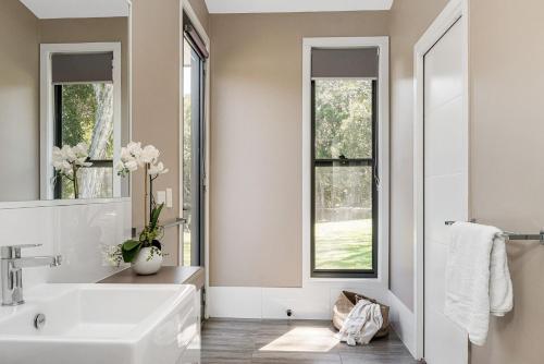 baño con lavabo y 2 ventanas en A Perfect Stay - Lennox Coastal Retreat, en Lennox Head