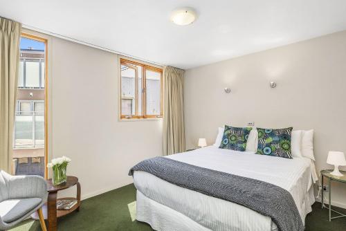 a white bedroom with a bed and a chair at Boutique Stays - Curran Terrace in Melbourne