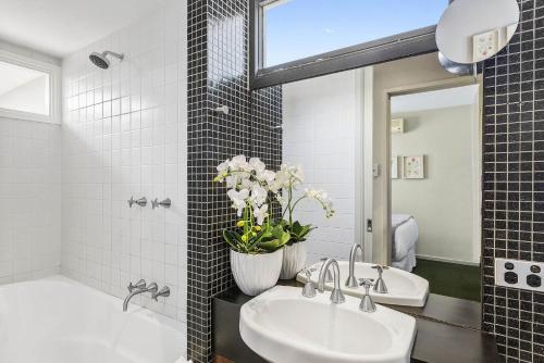 a bathroom with two sinks and a vase of flowers at Boutique Stays - Curran Terrace in Melbourne