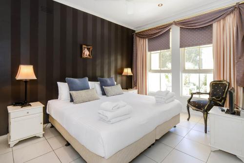 a bedroom with a large white bed and a chair at Brighton Rose in Melbourne