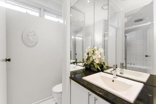a white bathroom with a sink and a mirror at Brighton Rose in Melbourne