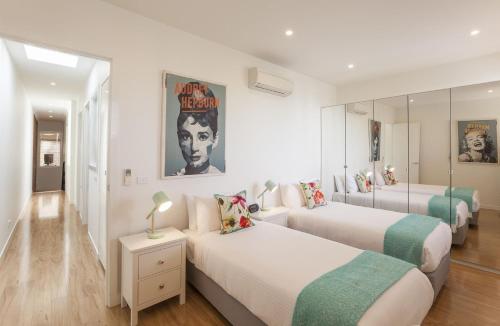 a bedroom with two beds and a mirror at Boutique Stays - Central Park in Melbourne