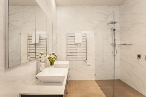 a white bathroom with a sink and a shower at Boutique Stays - Central Park in Melbourne