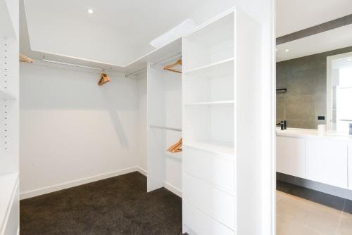 a walk in closet with white cabinets and a sink at Boutique Stays - Murrumbeena Place 2 in Carnegie
