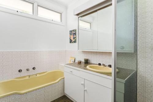 ein Badezimmer mit einem Waschbecken und einer Badewanne in der Unterkunft Boutique Stays - That 70s House in Mount Waverley