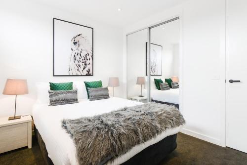 a white bedroom with a large bed with a furry pillow at Boutique Stays - Murrumbeena Place 2 in Carnegie