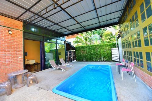 una piscina en un patio con sillas y un edificio en พาลาซิโอ เดอ ปราณี en Phetchaburi