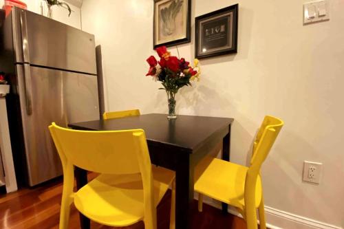 a dining room table with yellow chairs and a vase of flowers at Modern Cozy Unit Near Geno's & Pat's in Philadelphia