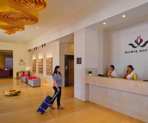 a woman walking through a hotel lobby with her luggage at Daiwik Hotels Rameswaram in Rāmeswaram