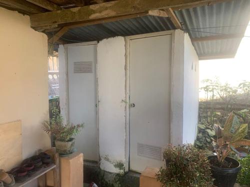 eine weiße Tür an der Seite eines Gebäudes mit Pflanzen in der Unterkunft Homestay Kurnia 