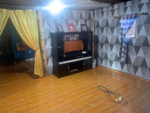 a living room with a tv and a wooden floor at Homestay Kurnia 