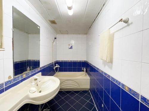 ein blau-weißes Badezimmer mit einem Waschbecken und einer Badewanne in der Unterkunft Seven Motel in Busan