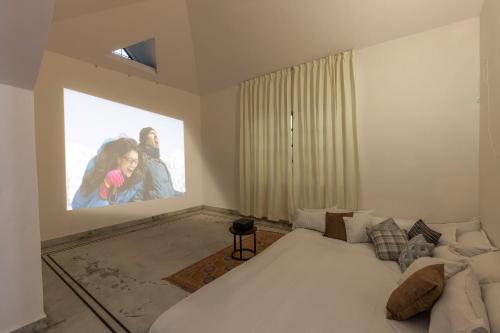 een slaapkamer met een wit bed en een film geprojecteerd op de muur bij Cozy 4BHK Villa in Bangalore