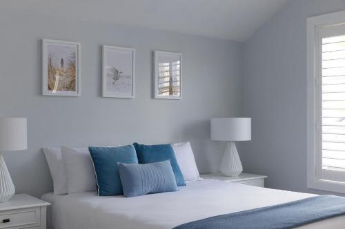 a white bedroom with a bed with blue pillows at Boutique Stays - Two Plus Two in Melbourne