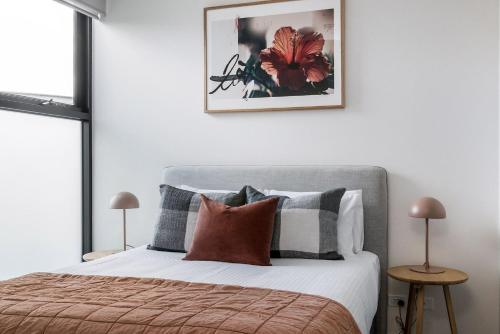 メルボルンにあるBoutique Stays - Axel Apartments 202 The Radnorのベッドルーム1室(枕付きのベッド1台、壁に絵付)