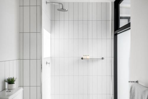y baño con ducha y paredes de azulejos blancos. en Boutique Stays - Axel Apartments 203 The Bonfield en Melbourne