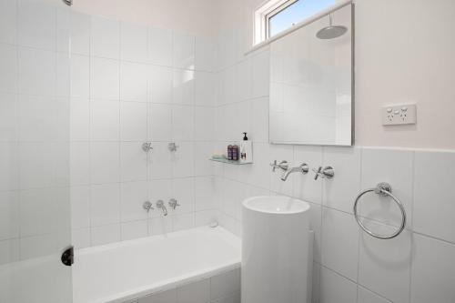 a white bathroom with a tub and a sink at Boutique Stays - Cherrybombe in Melbourne
