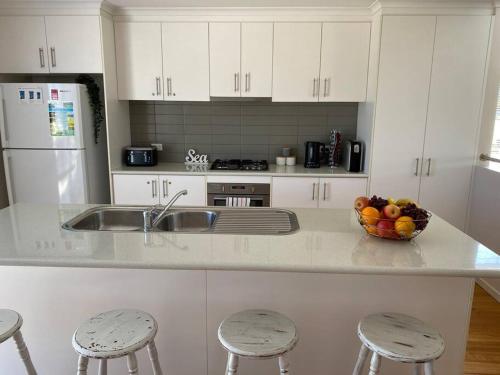 una cocina con armarios blancos y un bol de fruta en la barra en Twin Beaches Retreat Cowes, en Cowes