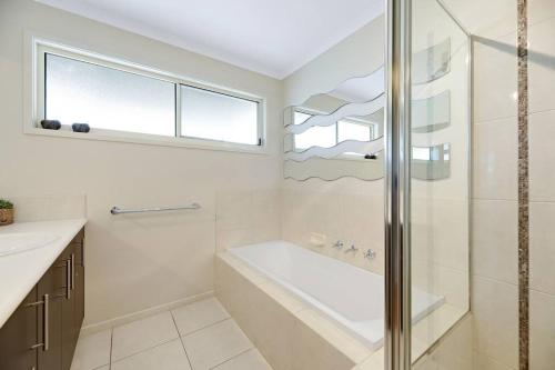 a bathroom with a shower and a tub and a sink at Twin Beaches Retreat Cowes in Cowes