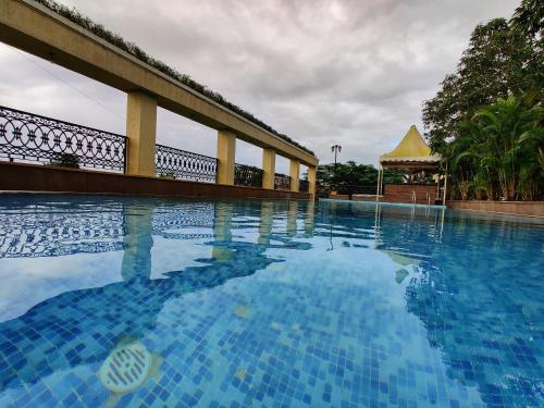a swimming pool with blue water and a gazebo at Misty Meadows, Lonavala in Lonavala