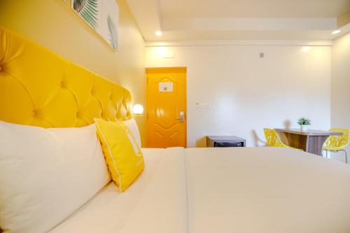 a bedroom with a large white bed with a yellow headboard at Bloom Hotel - HAL Old Airport Rd in Bengaluru