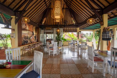 un restaurante con sillas y mesas blancas y techo en Nirmala Guest House Surf Keramas, en Keramas