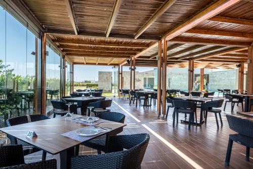 a restaurant with tables and chairs and windows at Astir Odysseus Kos Resort and Spa in Tigaki