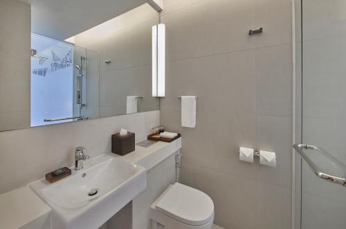 a bathroom with a sink and a toilet and a mirror at Aloft Singapore Novena in Singapore