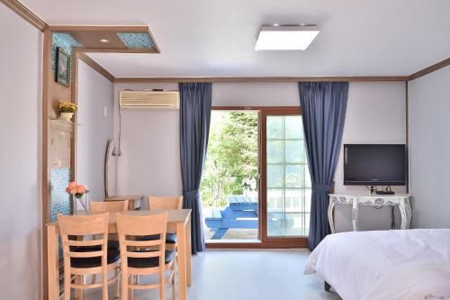 1 dormitorio con 1 cama, mesa y sillas en Yangyang Pulbit Pension en Yangyang