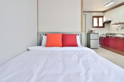 a large white bed with two red pillows on it at Yangyang Pulbit Pension in Yangyang
