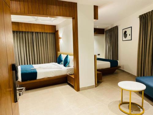 a hotel room with a bed and a table and a chair at Hotel Emora Tree in Mysore