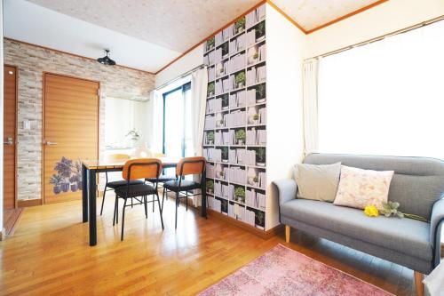 sala de estar con sofá, mesa y sillas en MATATABI STAY Alita Motomachi 3F, en Osaka