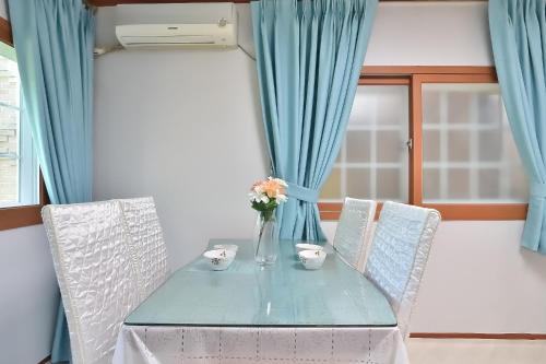a blue table with two chairs and a vase with flowers at Yangyang Pulbit Pension in Yangyang