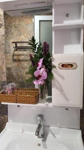 a bathroom sink with a vase of flowers and a mirror at Mina Thien Ha in Da Lat