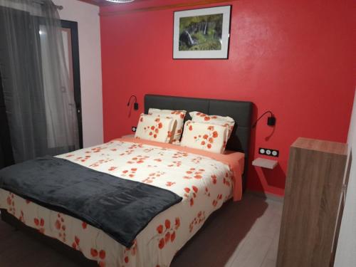 a bedroom with a bed with a red wall at LES SOMMETS DE SALAZIE CHAMBRES D'HÔTES in Salazie