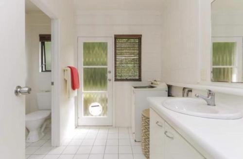 Baño blanco con lavabo y aseo en Scherff Road Holiday Home en Auckland
