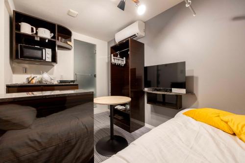 Schlafzimmer mit einem Bett, einem Tisch und einem TV in der Unterkunft HJ PLACE SHIBUYA in Tokio