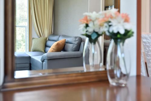 a mirror reflecting a living room with flowers in vases on a table at Yangyang Pulbit Pension in Yangyang