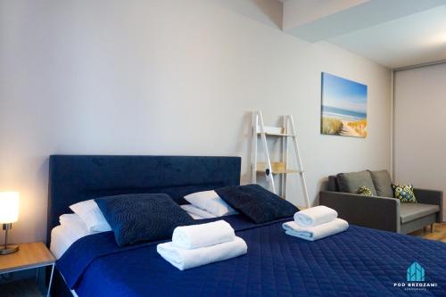 ein Schlafzimmer mit einem blauen Bett mit Handtüchern darauf in der Unterkunft Pod Brzozami Apartamenty Villa Solny in Ustronie Morskie